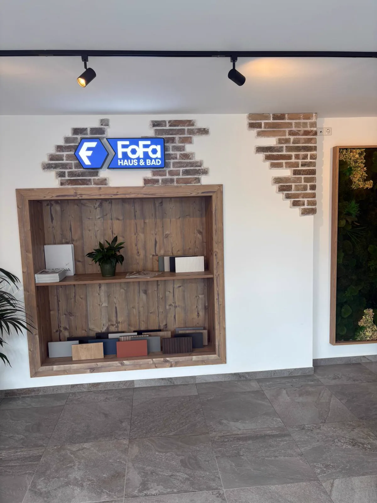 Eingangsbereich des Schauraums von FoFa Haus & Bad in Weistrach mit FoFa-Schild, Musterregal aus Holz und Mooswand