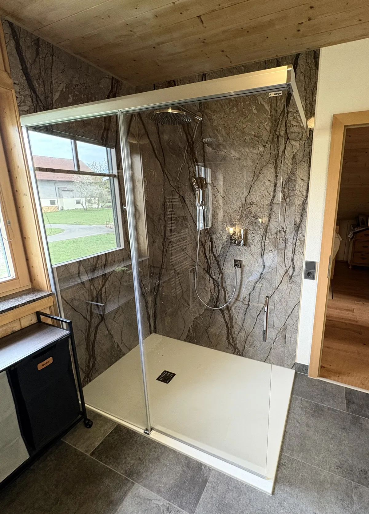 Nachher: großzügige Dusche mit Regenbrause und Wandpaneelen in Steinoptik, saniert von FoFa Haus & Bad